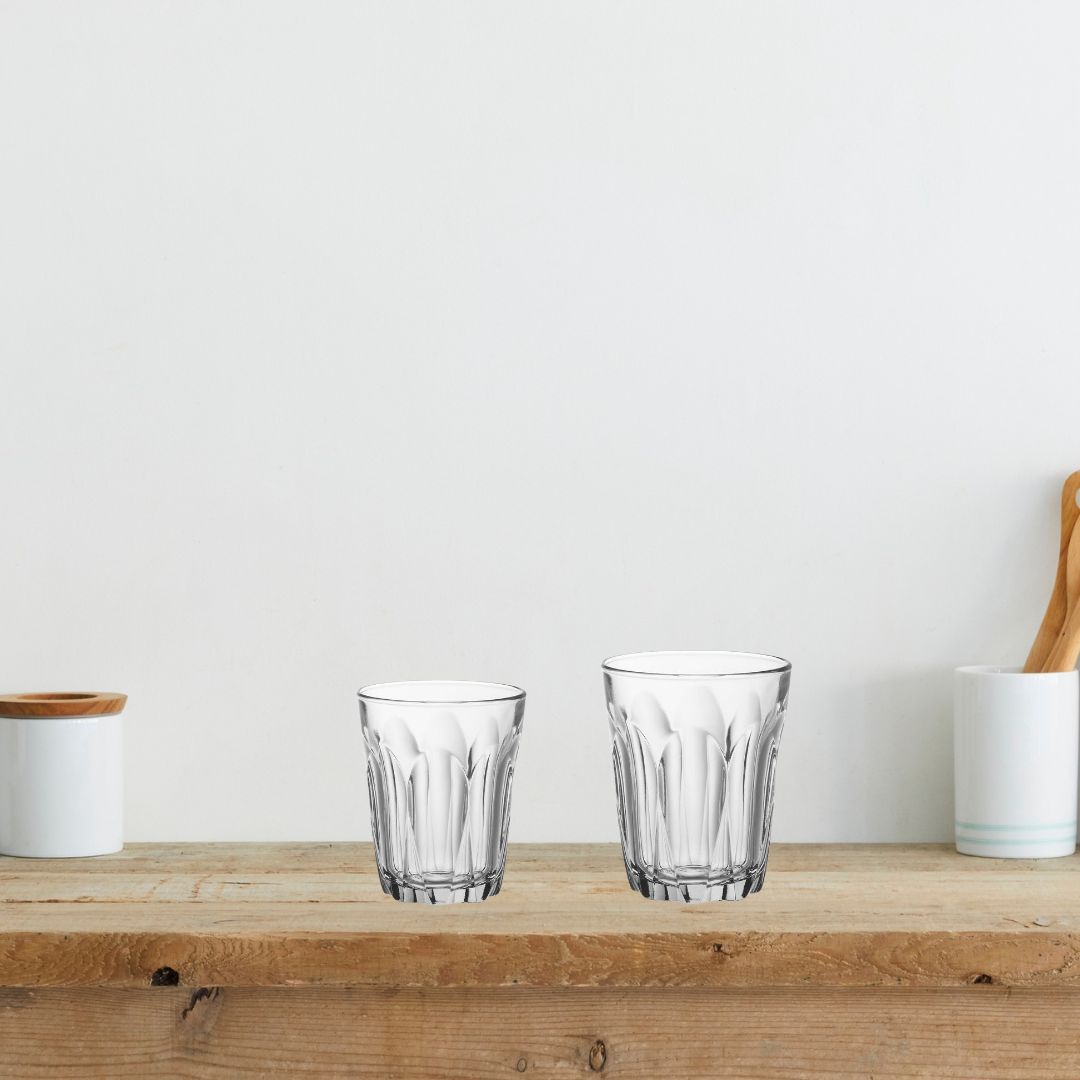 Two clear glass tumblers on a wooden surface with a white background
