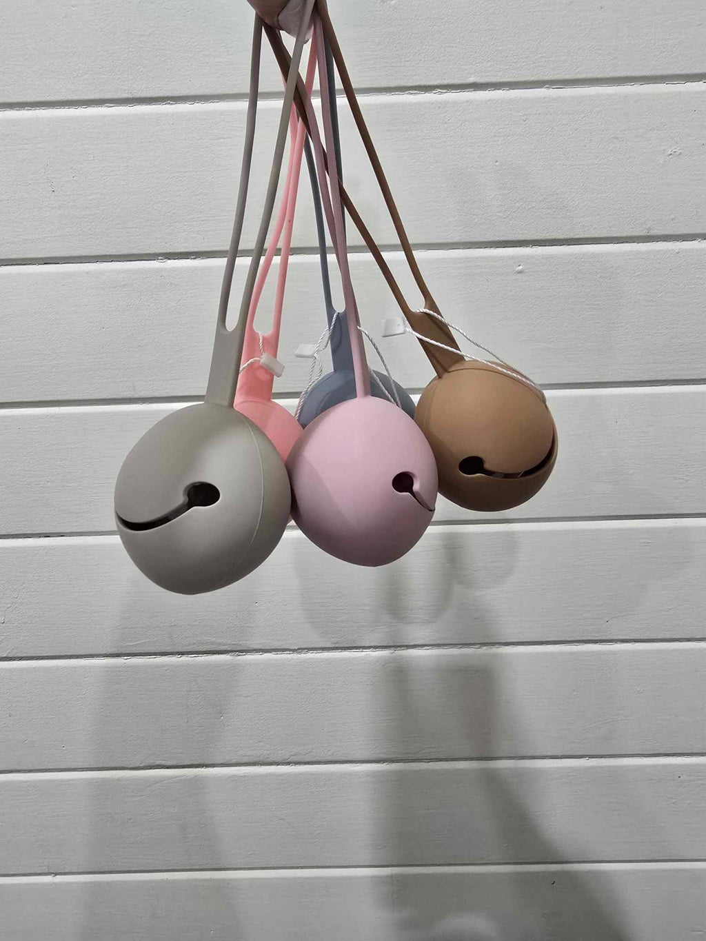 Set of four colorful dummy holders hanging against a light wooden background
