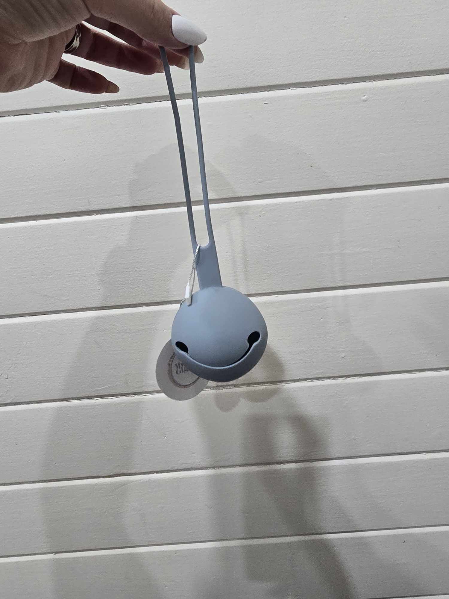 Gray dummy holder held by a hand on a light wooden surface