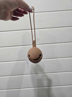 Smiley face dummy holder held by a hand against a light wooden panel background