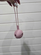 Pink dummy holder with a string held by a hand on a light wooden surface