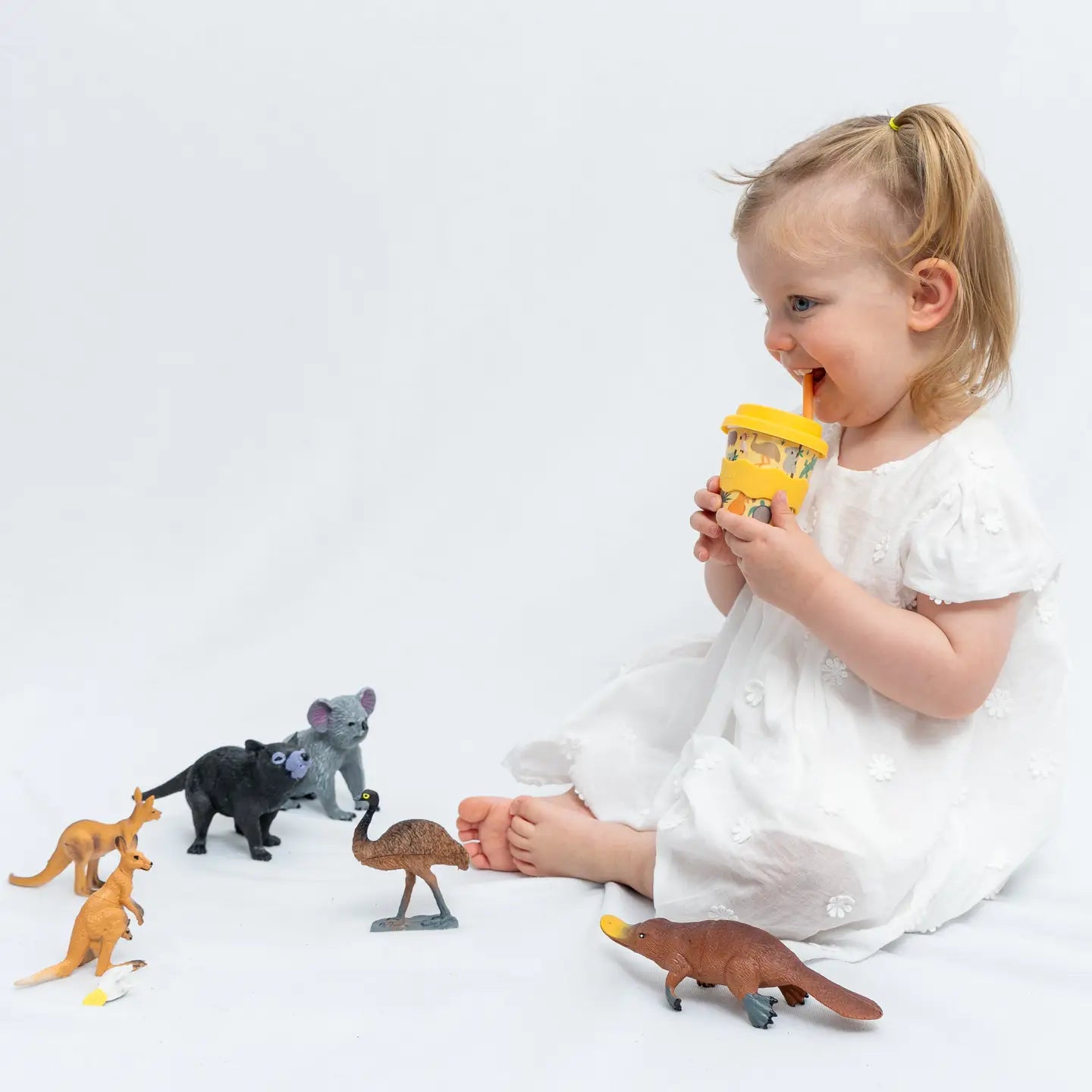Child playing with toy animals on a white background