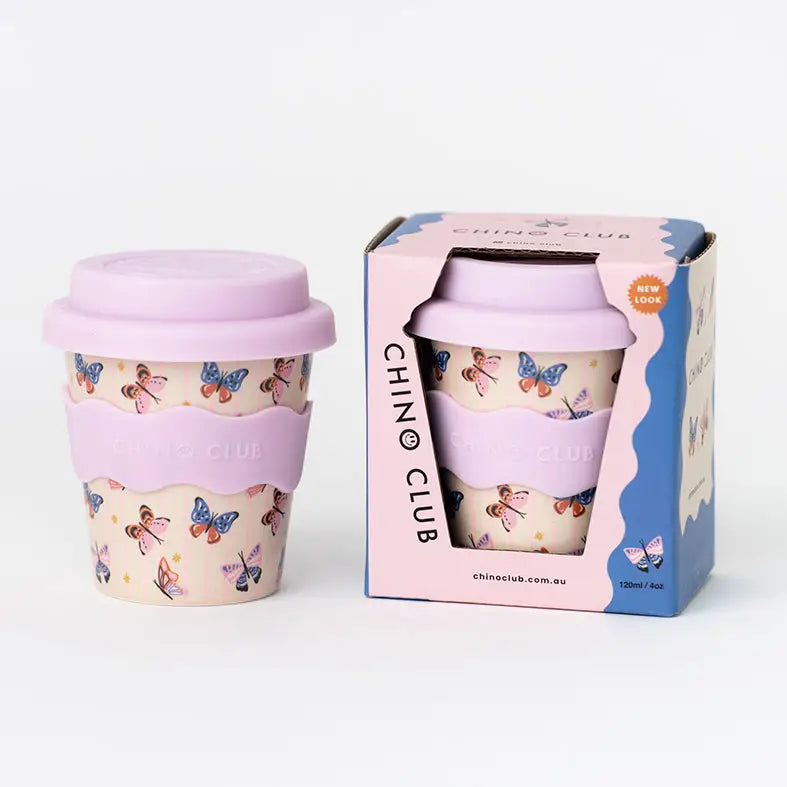 Reusable cup with butterfly design and pink lid next to its packaging box on a white background