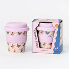 Reusable cup with butterfly design and pink lid next to its packaging box on a white background