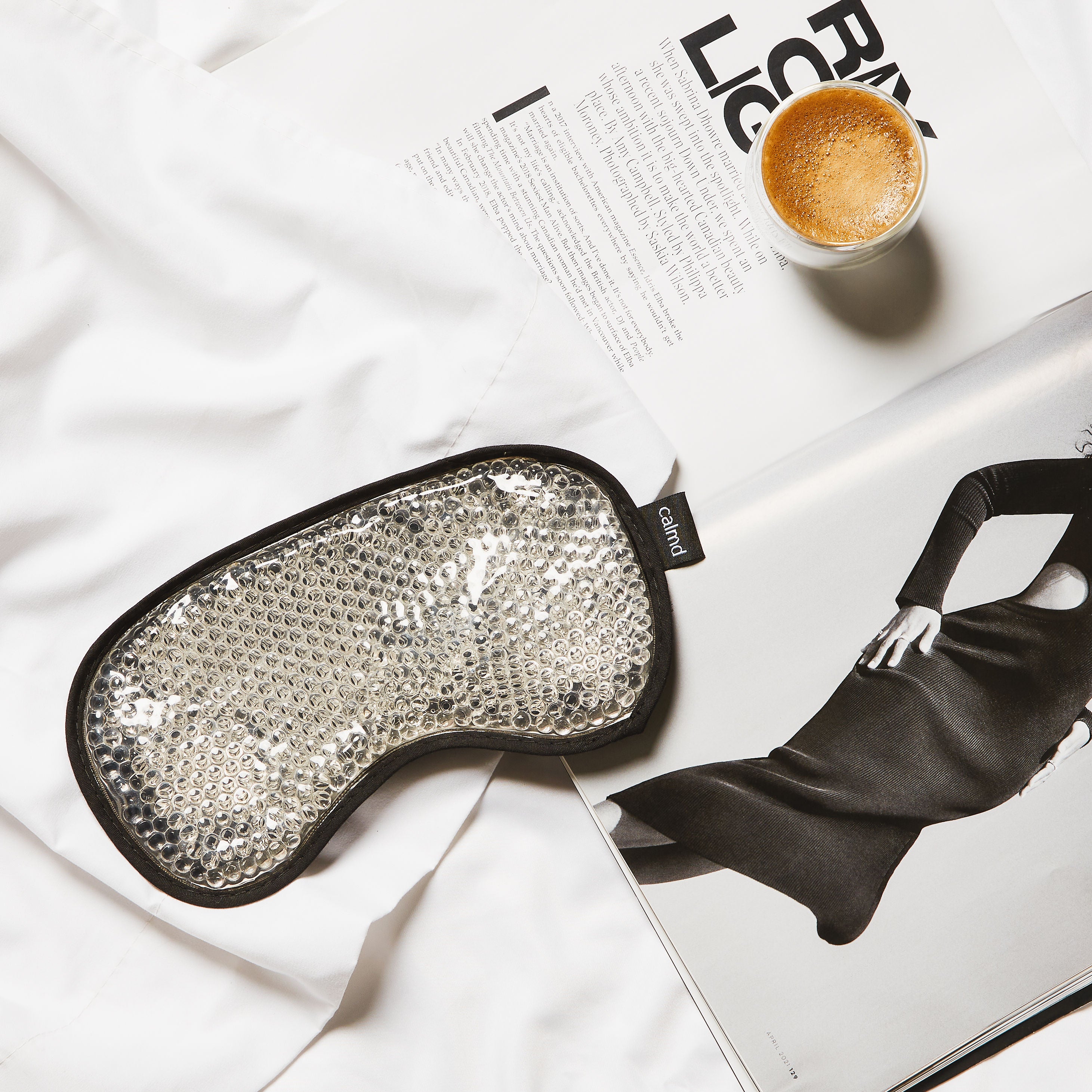 Silver eye mask on a magazine with a cup of coffee