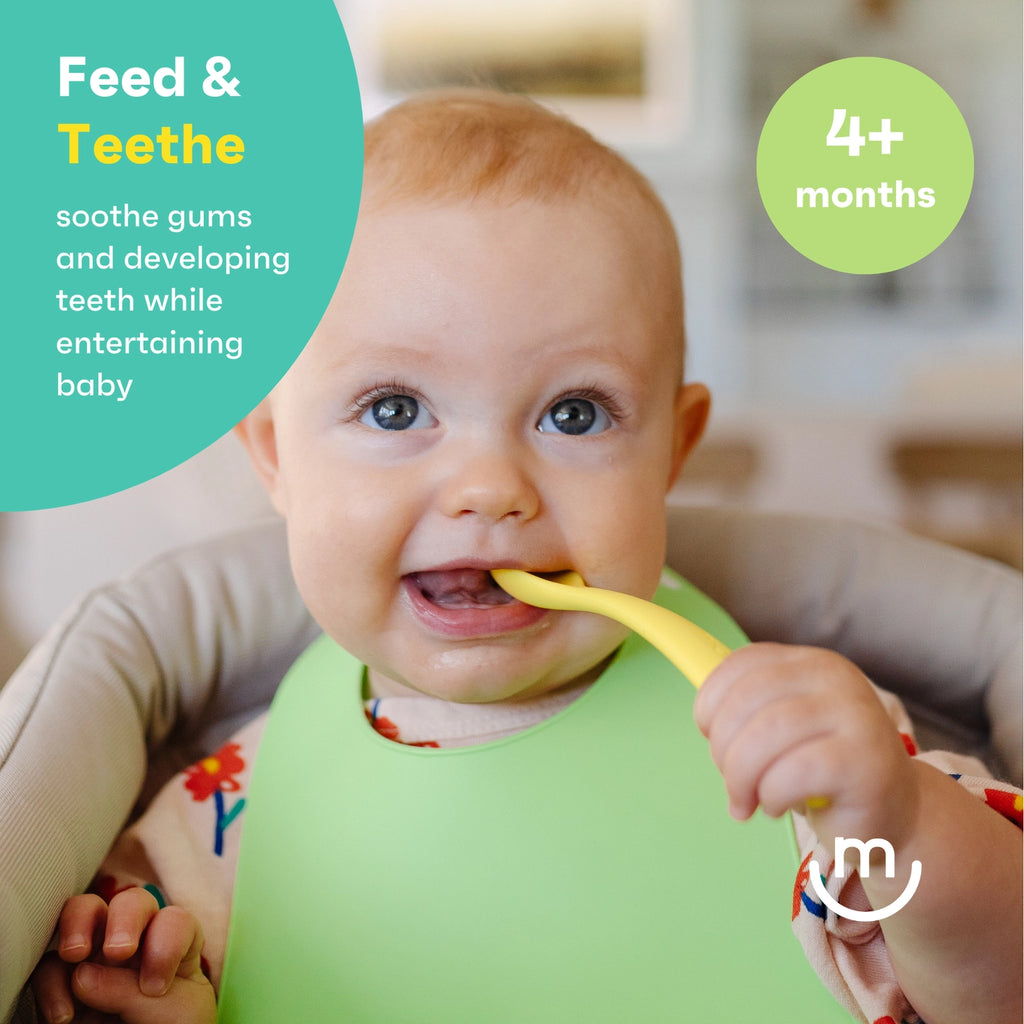 Baby wearing a green bib holding a yellow toothbrush with text about feeding and teething.
