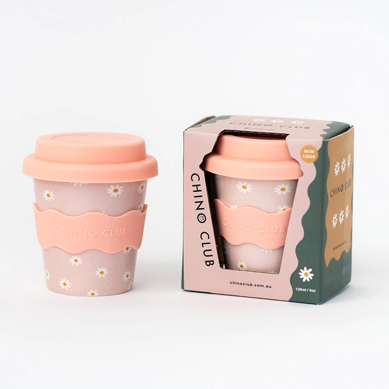 Pink reusable coffee cup with floral design and matching packaging on a white background