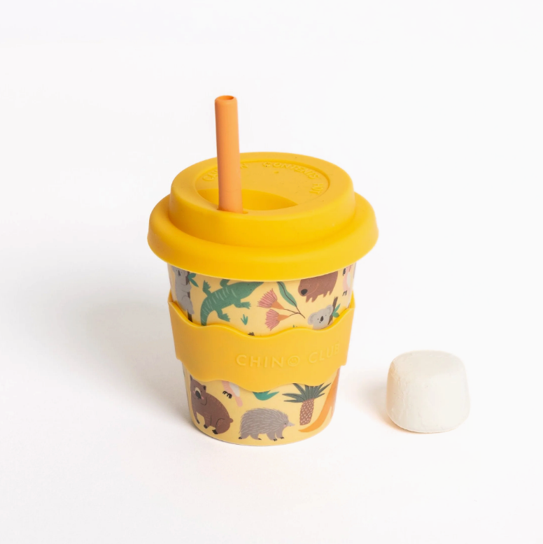 Yellow children's cup with dinosaur pattern and straw on a white background