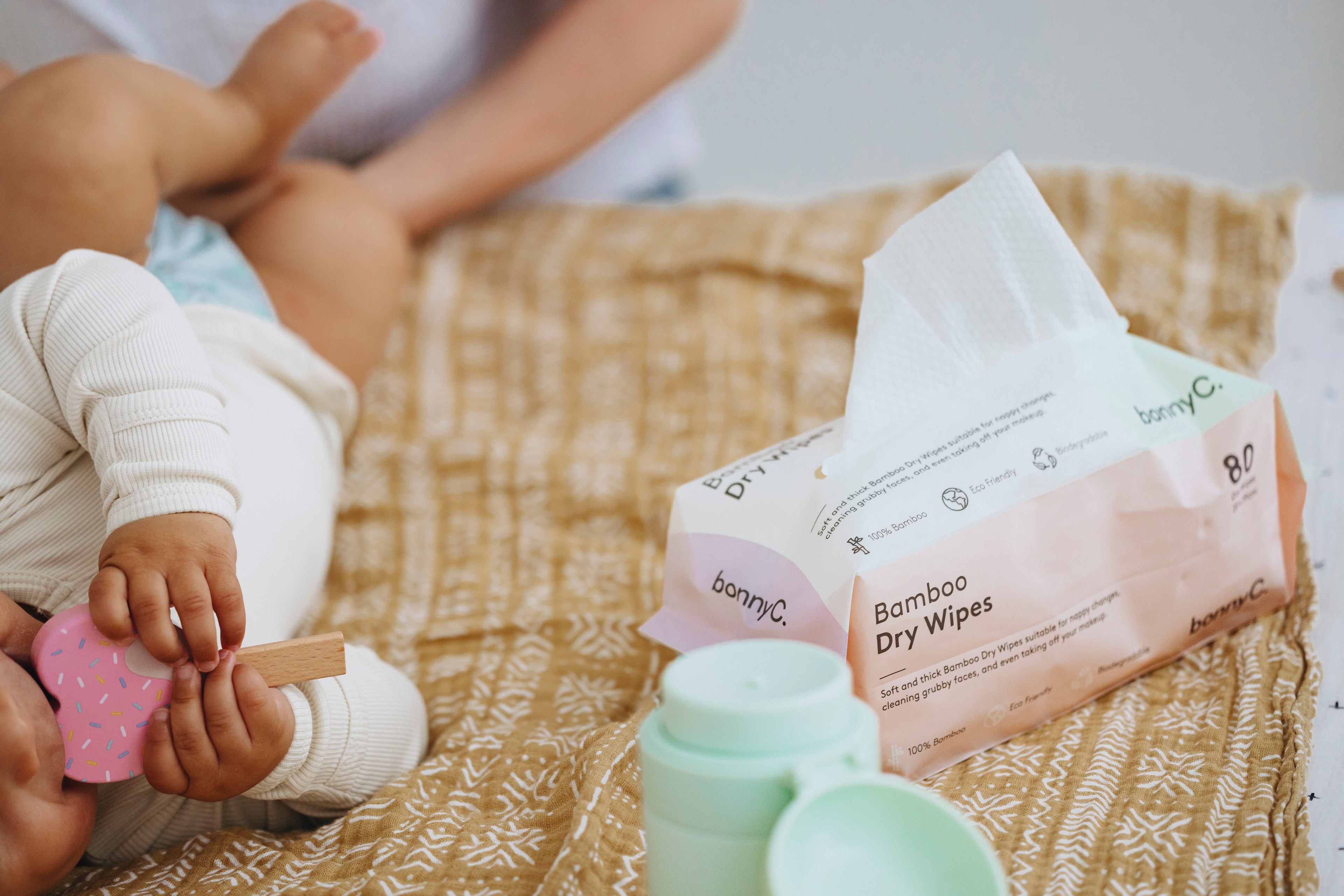Bamboo dry wipes on a textured surface with a child playing nearby.