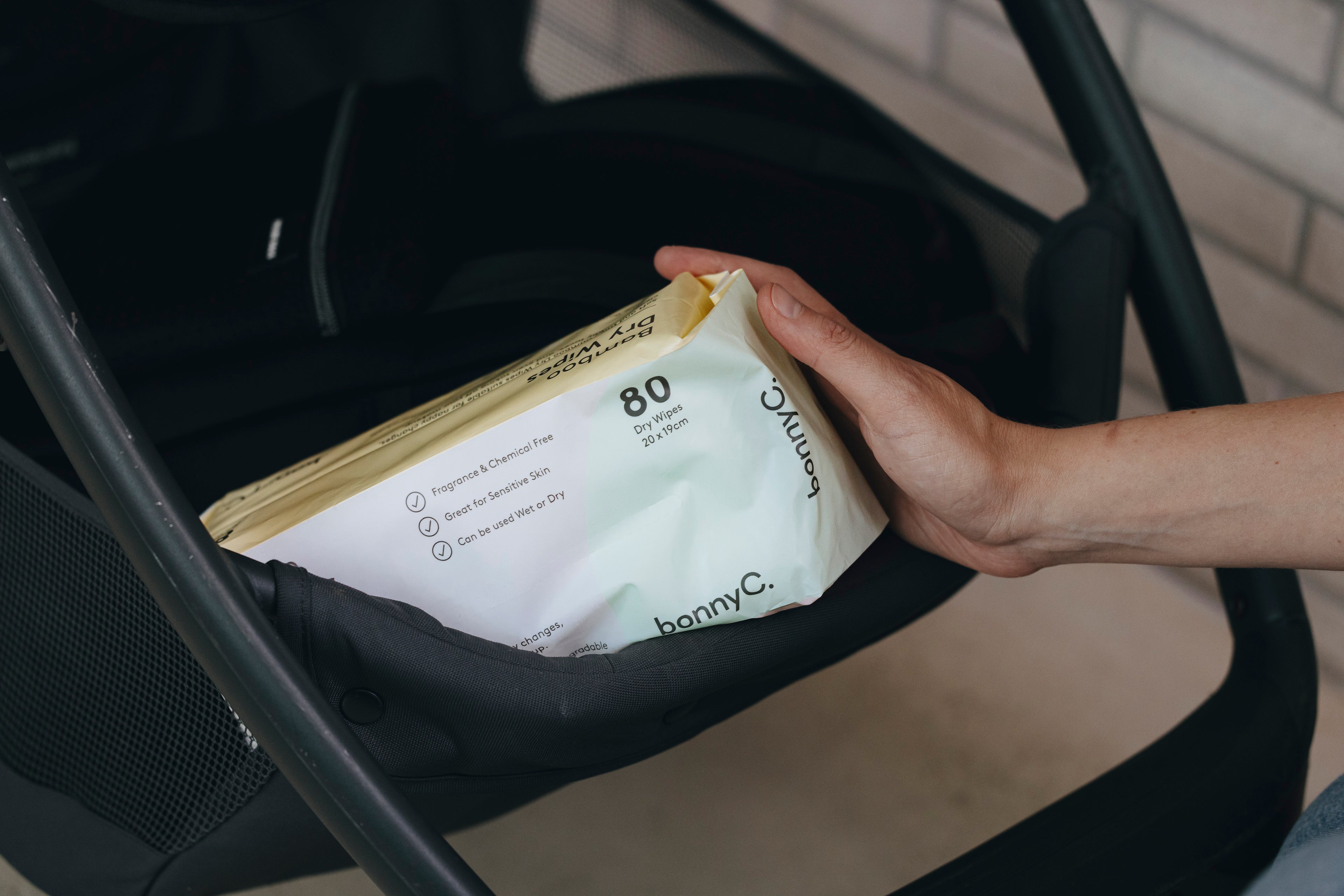 Hand holding a package of baby wipes inside a stroller.