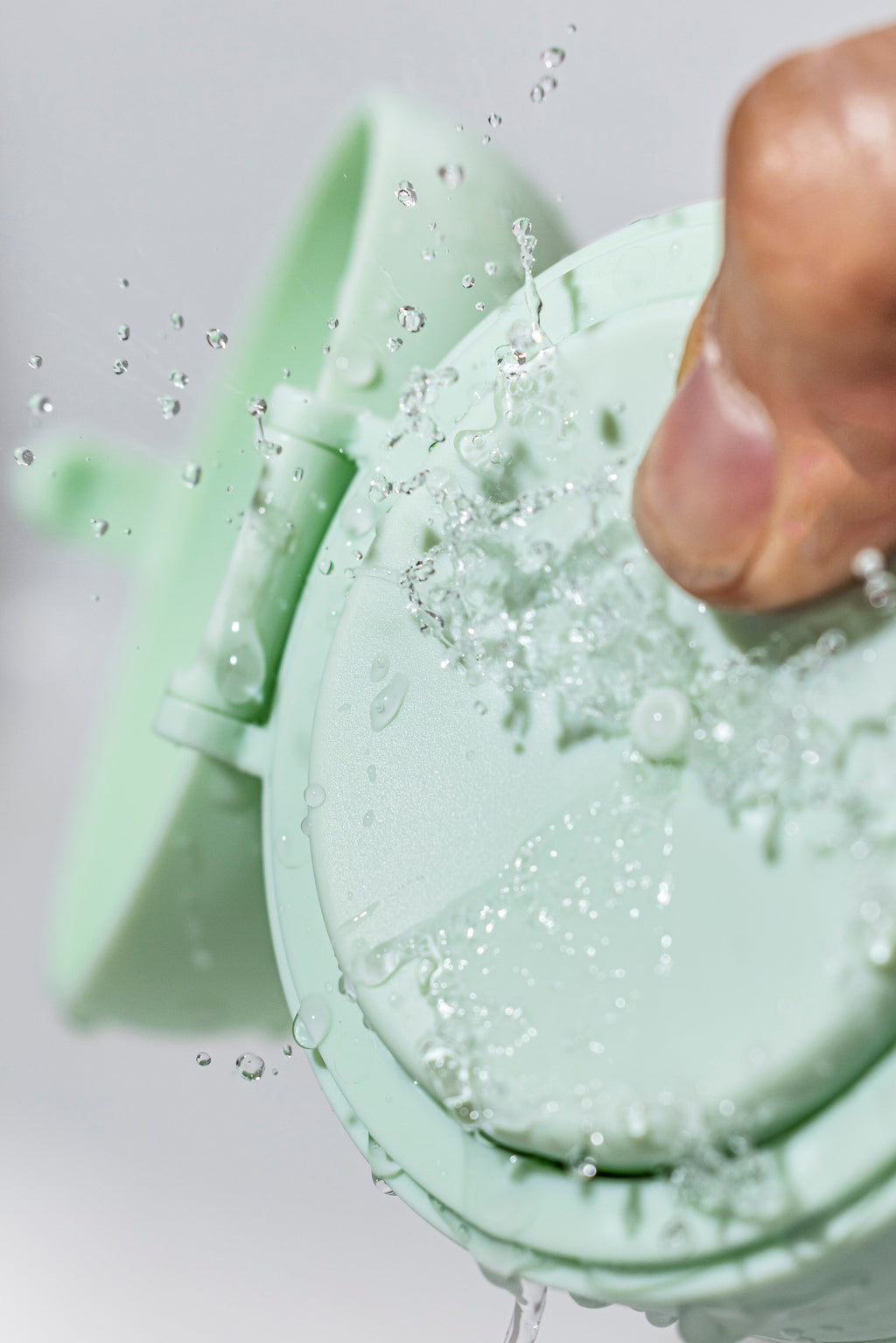 Green silicone mold with a hand pressing into it, filled with a bubbly green substance.