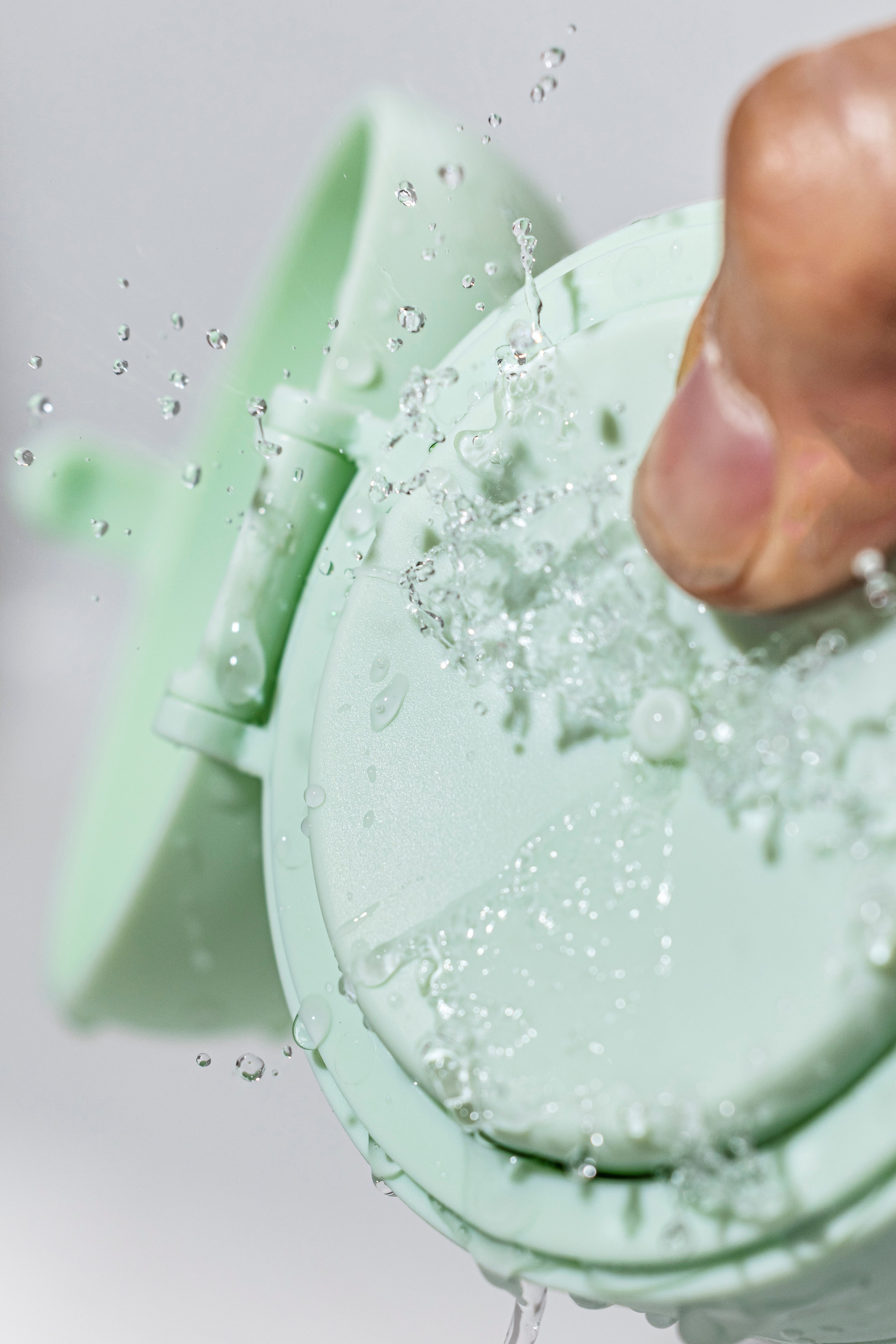 Green silicone mold with a hand pressing into it, filled with a bubbly green substance.