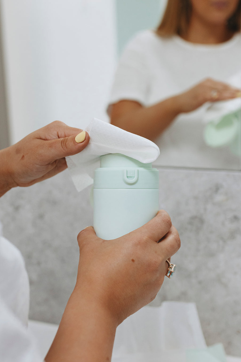 Person holding a water dispenser with a pump, possibly a skincare product, in a bathroom setting.