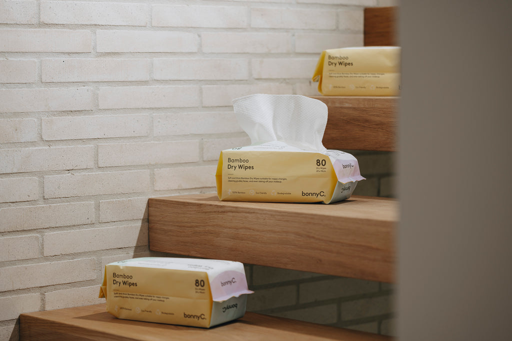 Bamboo dry wipes on a wooden shelf against a white brick wall.