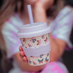 Person holding a patterned drink cup with a straw, brand 'CHING CHING' visible