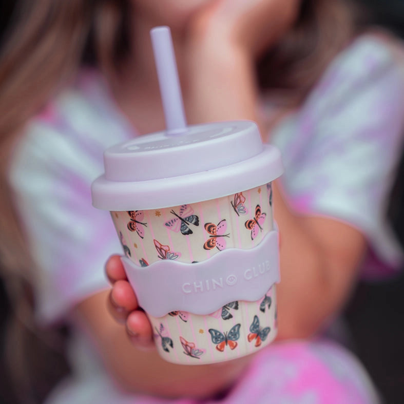 Person holding a patterned drink cup with a straw, brand 'CHING CHING' visible