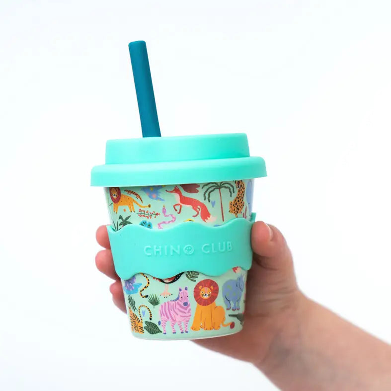 Hand holding a colorful tumbler with animal pattern and turquoise lid and straw on a white background