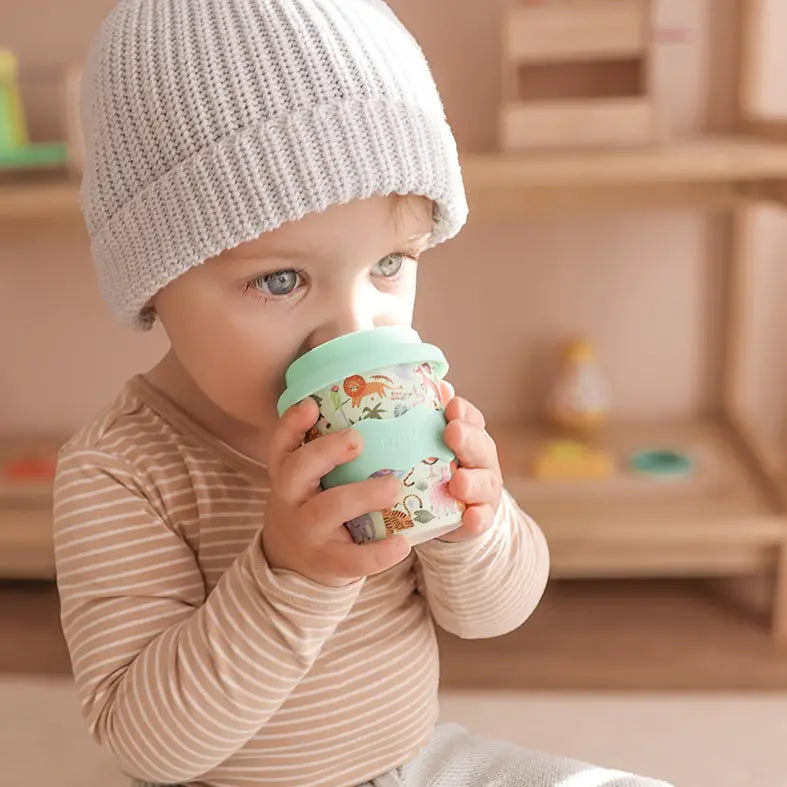 Child holding a light blue cup with floral design indoors
